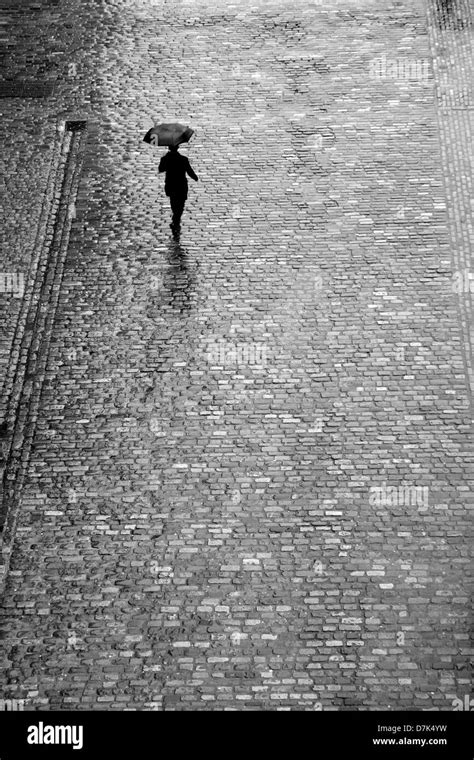 Pedestrian Walking In The Rain Across The Cobbles Of Covent Garden