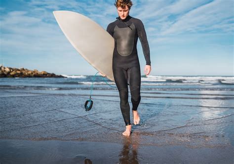 Retrato De Joven Surfista Dejando El Agua Con Tabla De Surf Bajo El
