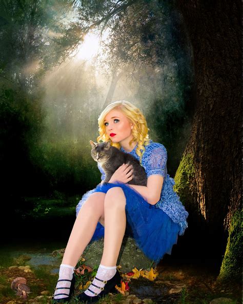 A Woman In A Blue Dress Is Holding A Cat And Sitting On The Ground Near