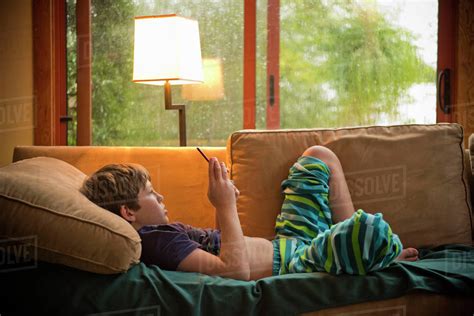 Caucasian Boy Laying On Sofa Texting On Cell Phone Stock Photo Dissolve