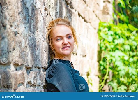 Portrait Of A Young And Beautiful Girl Near A Brick Wall Stock Photo