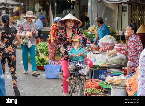 a vietnamese woman cycles with her son through the busy food market in cai rang near can tho