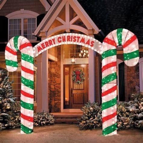 Two Large Candy Canes In Front Of A House Decorated With Christmas