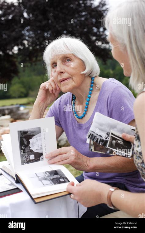 80 Year Old Woman With Her Daughter Looking At Photo Album Stock Photo