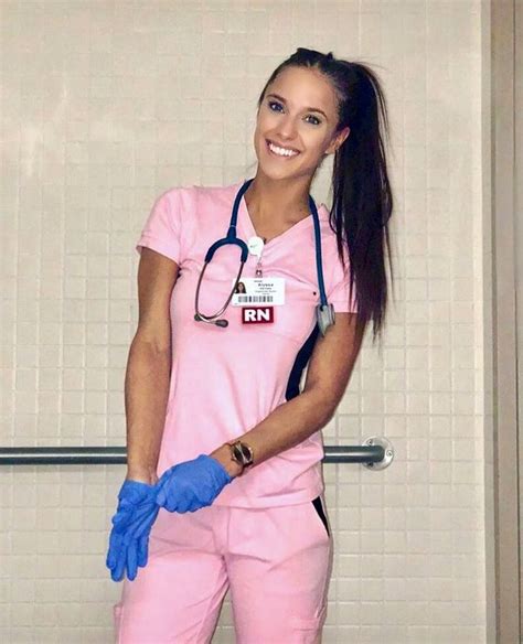 a woman in pink scrubs and blue gloves is posing for the camera with her hands on her hips
