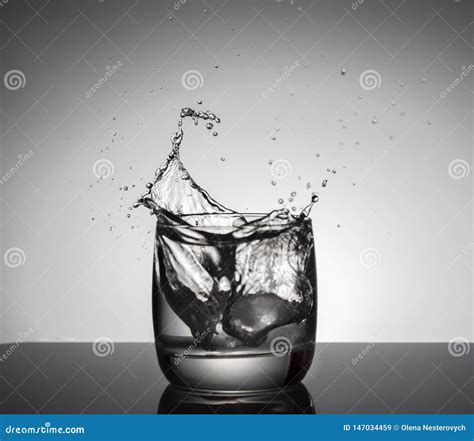 Ice Cubes Splashing Into Glass Of Water Fotografering För Bildbyråer