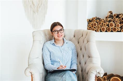 portrait of smiling caucasian woman psychologist sitting in armchair at the workplace holding a