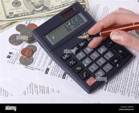 Female Hand Calculating Taxes On Calculator With W 9 Income Tax Forms