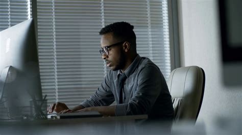 Side View Of Tired Black Man In Glasses Writing Texts Using Desktop Computer When Sitting At