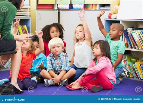 Group Of Elementary Pupils In Classroom Answering Question Stock Photo