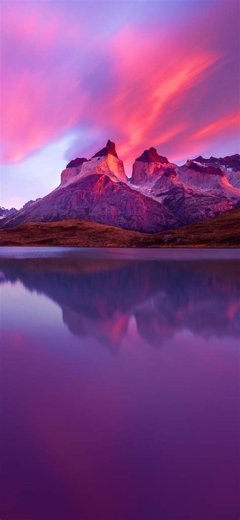 The Mountain Range Is Reflected In The Still Water At Sunset With Pink