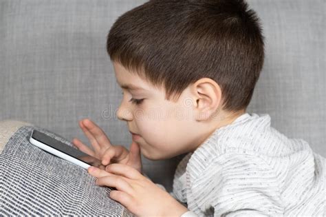 A Preschool Boy Uses A Smartphone Plays Games On His Phone Screen
