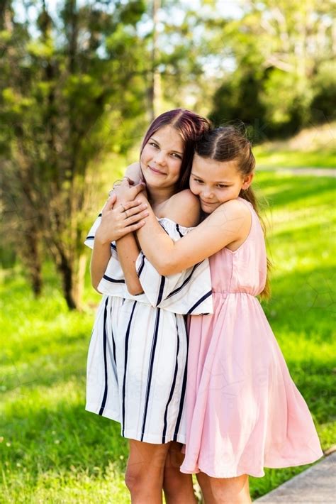 Image Of Happy Tween Sisters Hug Outside In Park Austockphoto