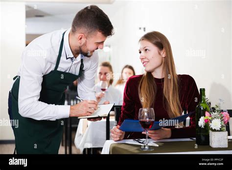 Waiter Is Taking Order From Young Female In Restaurante Indoor Stock