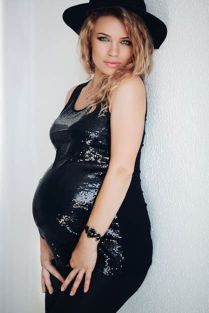Premium Photo Beautiful Pregnant Curly Blonde Woman In Shiny Black Dress And Hat