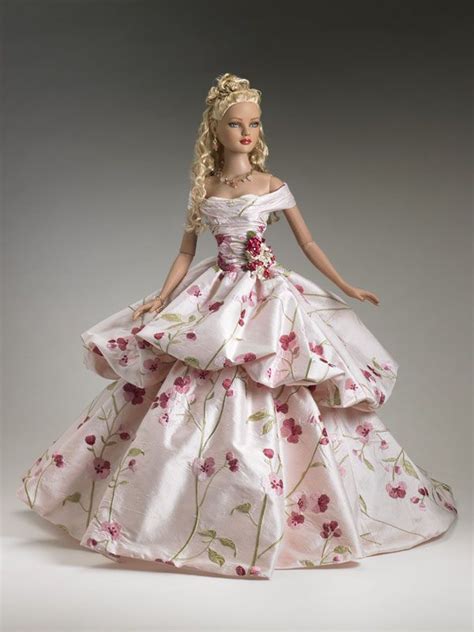 A Barbie Doll Dressed In A White Dress With Pink Flowers On Its Skirt