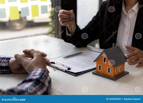 A Home Rental Company Employee is Handing the House Keys To a Customer