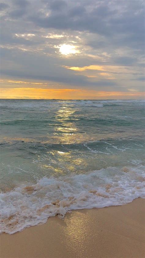 The Sun Is Setting Over The Ocean With Waves Coming In