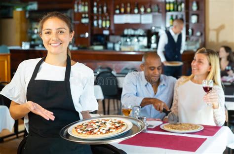 Portrait Of Smiling Waitress With Serving Tray Pizza At Restaurant