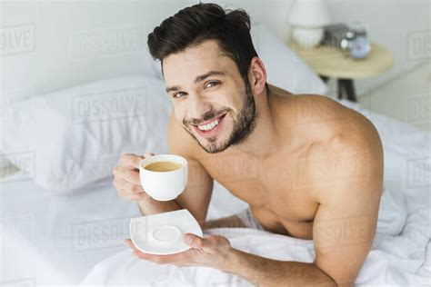 Handsome Smiling Man With Cup Of Coffee In Bed In The Morning Stock