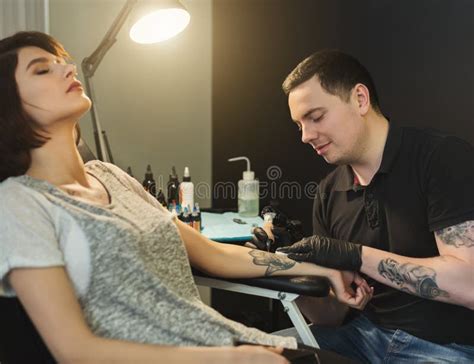 Painful Body Tattooing Process Master Working In Studio Stock Photo
