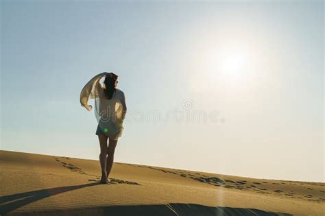 Woman Standing On Wavy Sand Dunes In Desert Landscape Stock Photo