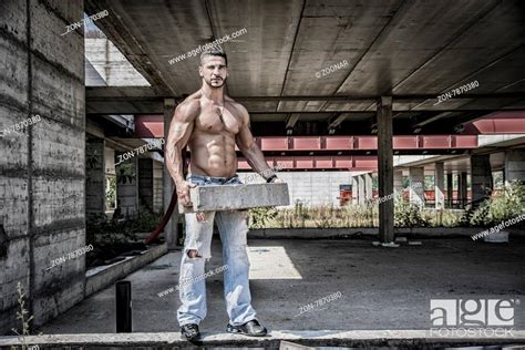 sexy construction worker shirtless showing muscular body holding big bricks foto de stock