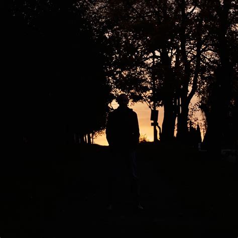 A Person Standing In The Dark Near Some Trees