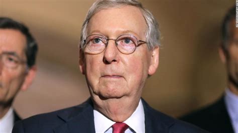 A tightly cropped photograph of discolored, purplish hands bearing a few small bandages, limply hanging from the sleeves of a black suit. Mitch McConnell Won on Tax Reform, But How? - USA Herald