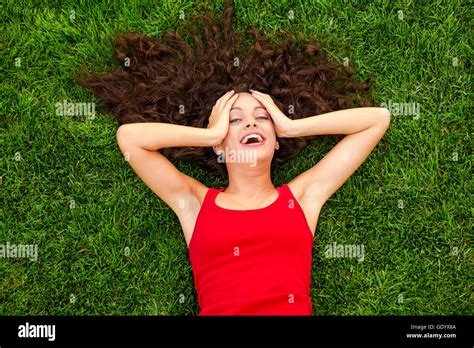 Outdoor Portrait Of A Beautiful Young Woman Lying On The Grass Stock