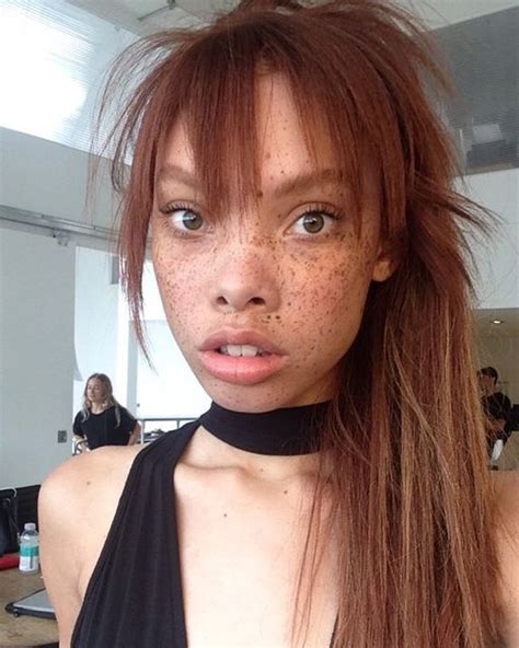 A Woman With Freckles On Her Face Is Posing For The Camera While Wearing A Halter Top