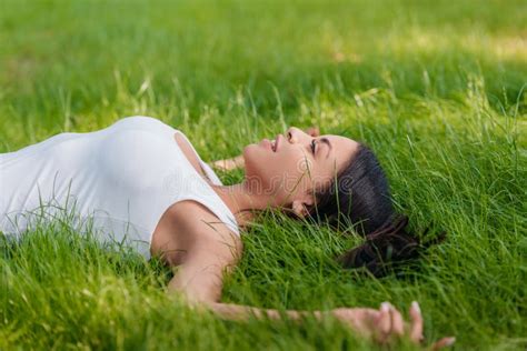 Smiling Woman Lying On Green Grass With Outstretched Arms Stock Image