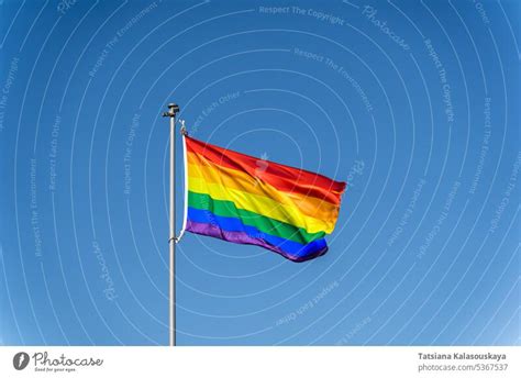 The Rainbow Flag Of The Lgbtq Community Flies Against Blue Clear Sky A Royalty Free Stock