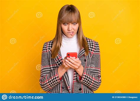 Photo Of Unsatisfied Girl Biting Lips Look Phone Bad Fake News Unfollow Isolated On Yellow Color