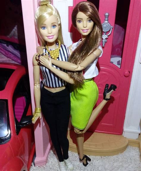 Two Barbie Dolls Standing Next To Each Other In Front Of A Pink Door And Car