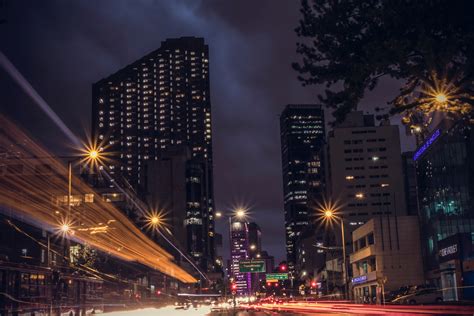 A Dark City Background Featuring Large Buildings And Street Light