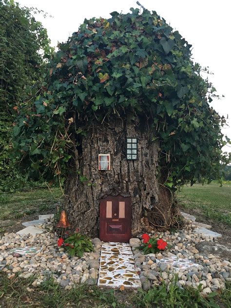 A House Made Out Of A Tree Trunk With Ivy Growing On Its Roof