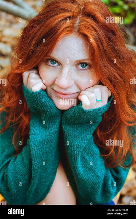 Portrait Of A Beautiful Red Haired Girl With Freckles And Blue Eyes In Colorful Autumn Park