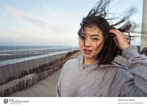 Junge Asiatin Steht Bei Windigem Wetter Am Meeresstrand Ein Lizenzfreies Stock Foto Von Photocase