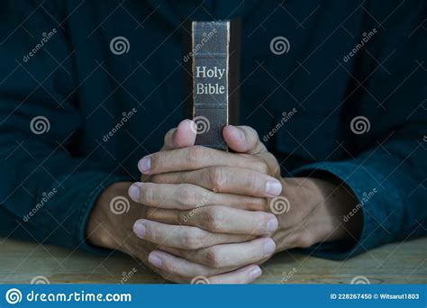Christian Man Holding Bible Hands Folded In Prayer On A Holy Bible On
