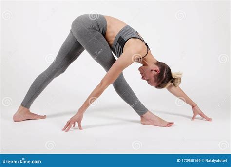 Young Woman Practicing Yogastanding In Exercise Leaning Forward To