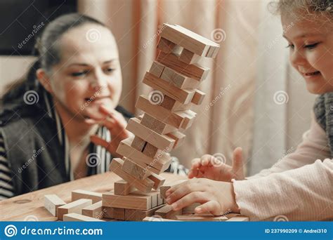 Mom And Daughter Play A Board Game Build A Tower From Wooden Blocks