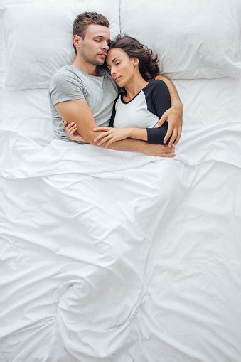 Above View Of Young Romantic Couple Hugging In Bed While Sleeping Stock