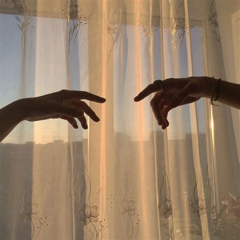 Two Hands Reaching Towards Each Other In Front Of Curtains