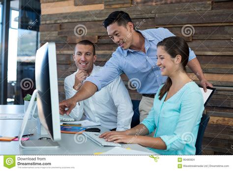 Businesspeople Interacting While Working On Personal Computer Stock