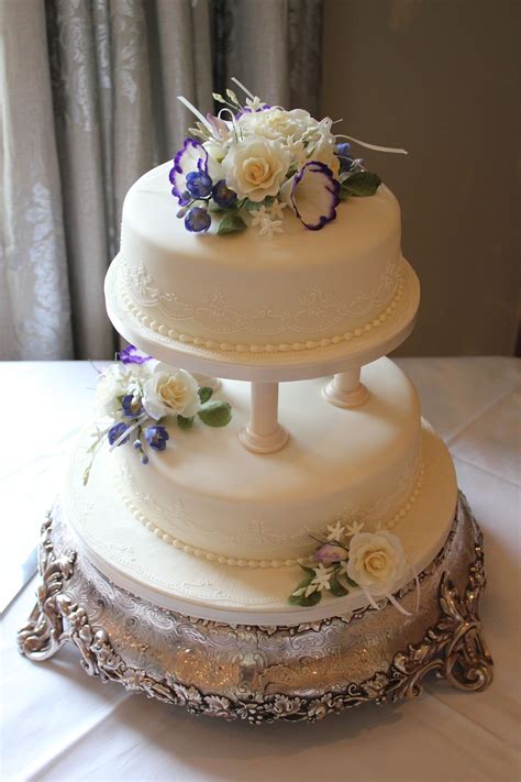 A Two Tier Cake With Pillars And Icing Flowers To Create This Beautiful