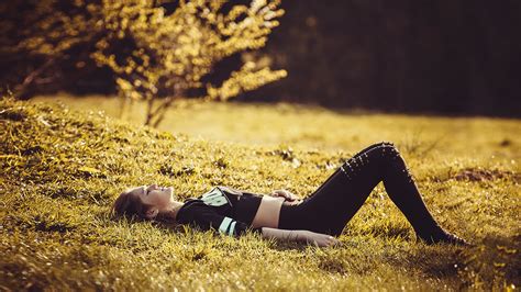Online Crop Woman Lying On Grass With Her Eyes Shut And Her Legs Bent