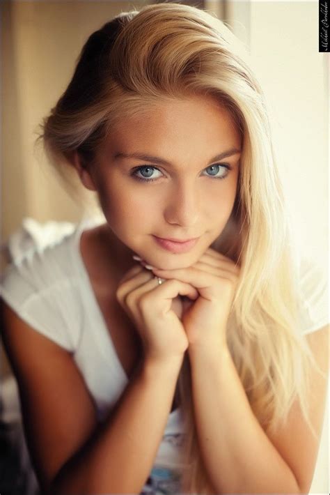 A Beautiful Blond Woman With Blue Eyes Posing For A Photo