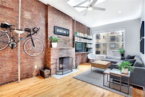 In this picture, the warm tones of the exposed brick wall add an organic touch to the room and cleverly complements the generous view of the greenery outdoors. Living Room with Brick Veneer Wall - DECOREDO