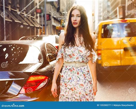 Beautiful Brunette Woman Walking On New York City Street Between Cars Wearing Summer Dress At